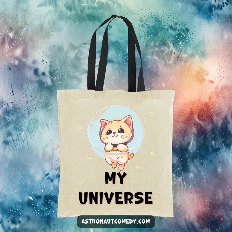Funny tote bag showcasing a curious cat in a bubble helmet floating through space, looking at stars.